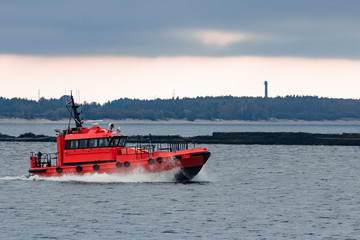 Fototapeta premium Red pilot ship moving at speed to Baltic sea in Riga, Europe