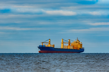 Fototapeta premium Blue cargo ship moored in still Baltic sea water