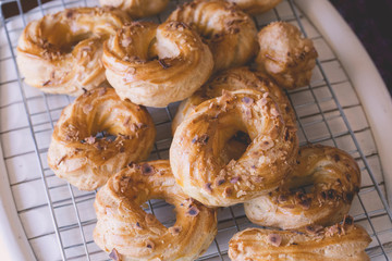 Freshly baked profiteroles filled in with vanilla cream and covered with roasted almonds on rustic wooden board, close up