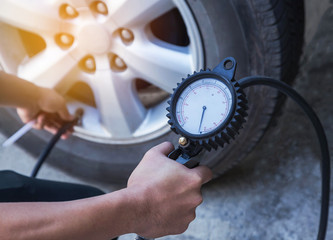 Close up mechanic inflating tire and checking air pressure with gauge pressure 