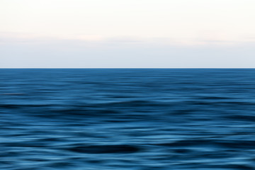 An abstract long exposure pan of the blue ocean and horizon.