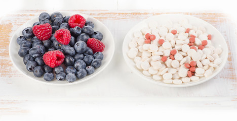 Pills or fresh berries. Choice from sources of vitamins. Nutrients.