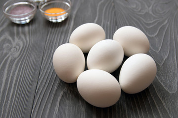 White chicken eggs and color dyes on a gray table. Celebrating Easter