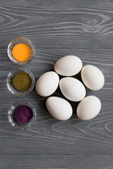 White chicken eggs and color pigments on a gray table. Celebrating Easter