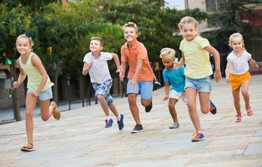 Fototapeta premium kids actively playing and running together on street on summer day