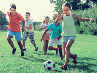 kids kicking football in park