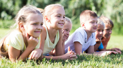 Fototapeta premium portrait of children lying on grass in park and looking happy