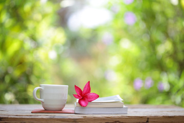 Books with flowers and cup on wooden table