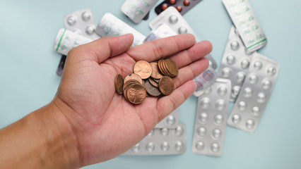 Stack of US dollar coin in man's hand with blur drug pack as background refer to cost of health care