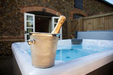 Fototapeta na wymiar bottle of champagne cooling by hot tub - romantic relaxing holiday concept
