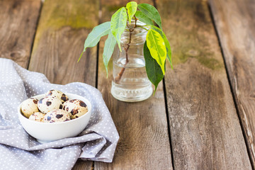 Quail easter eggs and flower on wooden table.