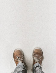 Man's legs in worn, soaked boots and trousers, crusted with sand on windy beach. Texture, background, vertical. Walking into unknown metaphor.
