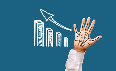 A painted electric light bulb on a man's palm with open fingers with a growing financial profit schedule. A creative idea in business