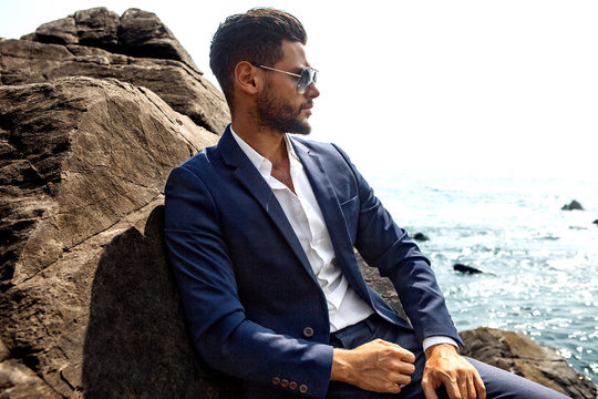 Man in elegant suite posing in rock background