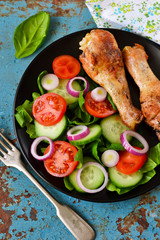 Baked chicken with a side dish of vegetable salad on the old, blue background