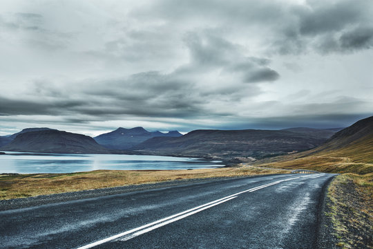 The road leads to the sea bay and mountains. The picture was taken by a cloudy cloudy day in autumn