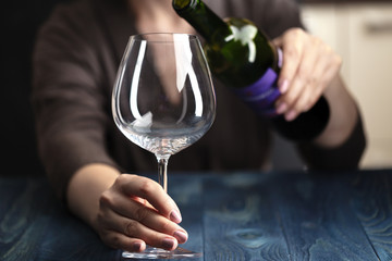 Depressed woman pouring wine on dark background