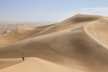 Fototapeta na wymiar young man walking in the sand dunes of Liwa desert