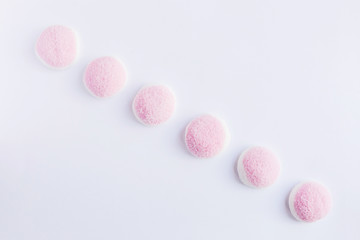 A few pieces of pink and white candy and jelly is on a white background