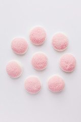 A few pieces of pink and white candies and jelly on white background