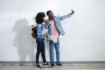 Couple taking selfie on a mobile phone while their friends interacting in background