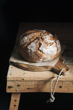 Homemade bread on cutting board and dark background
