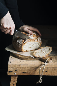 Woman cutting homemade bread with dark background