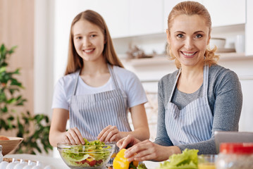 Joyful smiling woman cooking with her daughter