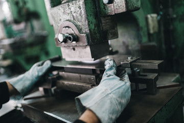 Metallurgy heavy industry. Factory for production of heavy pellet stoves and boilers. Worker hands close up. Extremely dark conditions and visible noise. Focus on foreground.