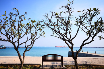 Fototapeta na wymiar Long wooden chair looking at the sea