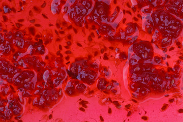 Macro shot of a spilled raspberry jam with berries and bones