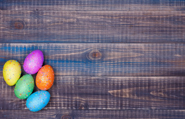 Easter background. A bunch of Easter eggs lies in a corner on a wooden background. Place for text