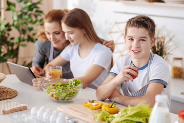 Pleasant smiling boy resting in the kitchen with his family