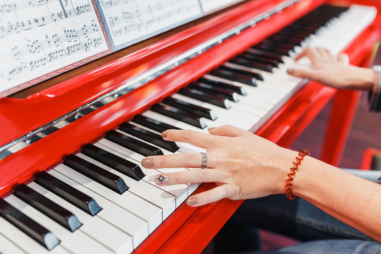 Close up of a woman's hands playing a red piano - creative, and music concept