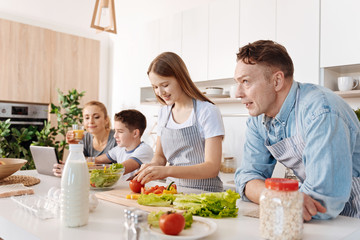 Positive girl cooking with her caring father