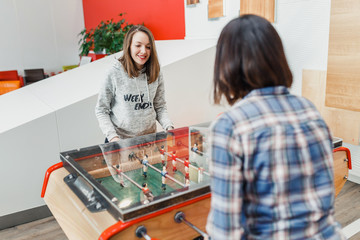 Two happy women friends playing table football at leisure time