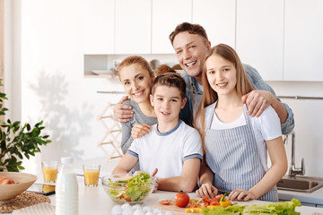 Happy smiling family standing together in the kitchen