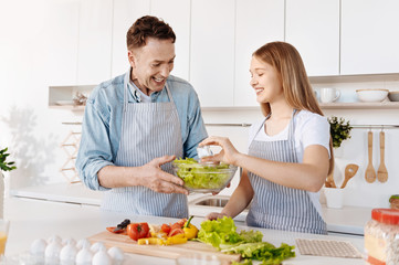 Positive smiling father and daughter having fun in the kitchen
