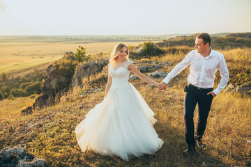 Fototapeta na wymiar wedding couple running and having fun in mountains in sunset light