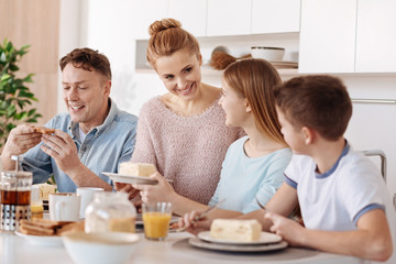 Obraz na płótnie Canvas Positive friendly family having breakfast in the kitchen