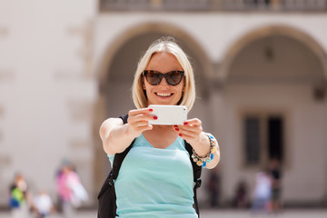 Female traveler on the background of Arcades in Wawel Castle in Cracow. Poland. Renaissance. A woman is photographed on her phone against the background of the castle courtyard