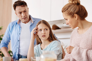 Cheerless moody girl discussing problems with her parents