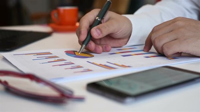 Businessman Analyzing Stock Market Diagrams On Cellphone And Paper. Slow Motion Effect