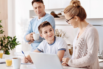 Pleasant little boy doing homework with his mother