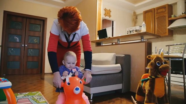 Grandmother swings baby on the toy cow