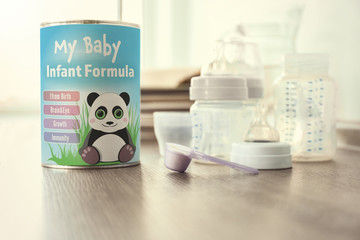 Baby milk formula in spoon on wooden table, closeup