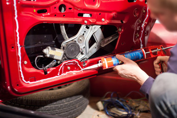 A man applies sealant to the car door
