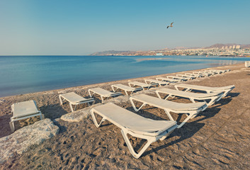 Fototapeta na wymiar Sandy beach with deckchair waiting for tourists in Eilat -famous resort in Israel and Middle East