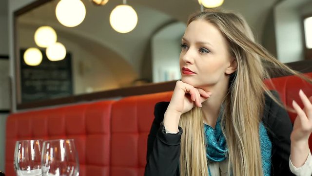 Elegant, beautiful woman relaxing in posh restaurant and looks reflective
