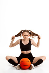 Young pretty girl posing with basketball over white background.